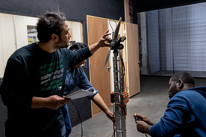 Three students working on a airplace turbine