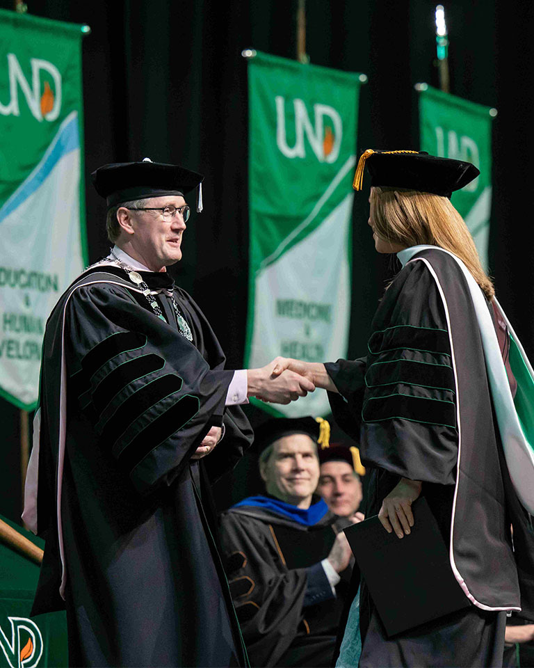 und president shaking someone's hand at graduation