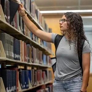 A student browsing the library stacks