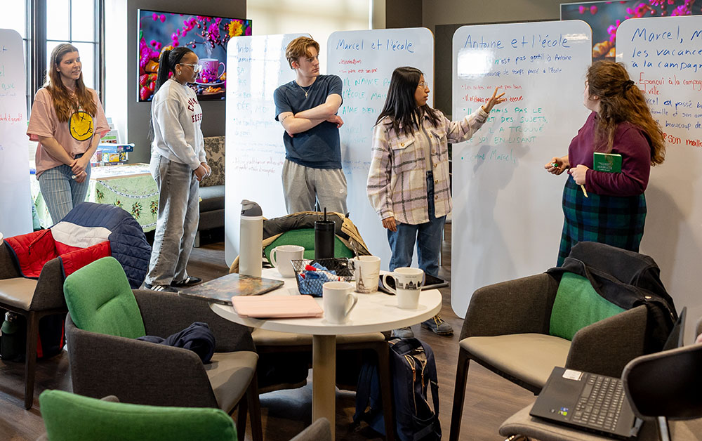 Group of students standing in front of whiteboards in a classroom.