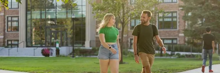 Two students walking through the quad on UND's campus with Merrifield Hall in the background