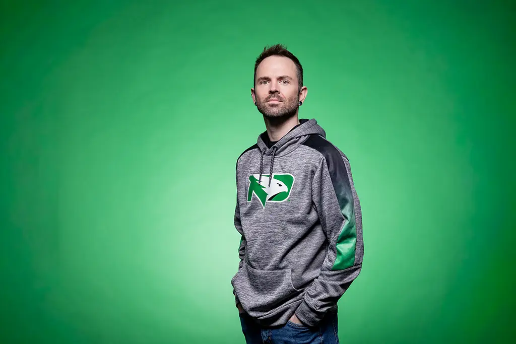 Austin stands in front of a green backdrop looking at the camera