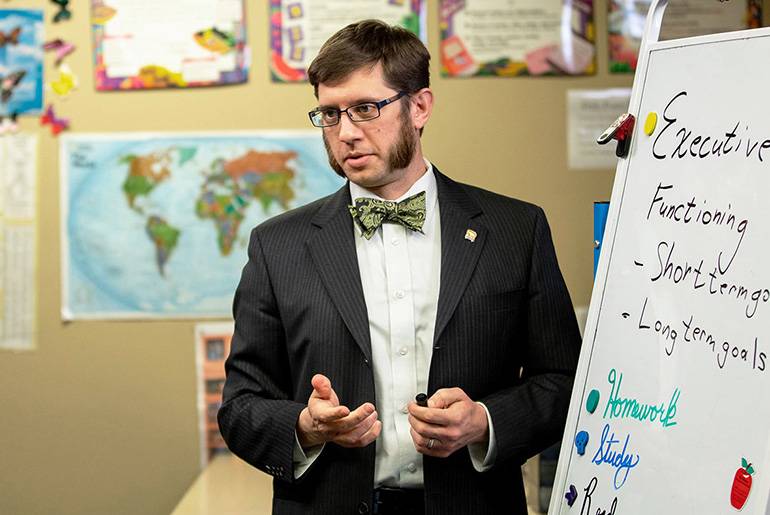 Special Ed grad Dennis Bolda in front of white board