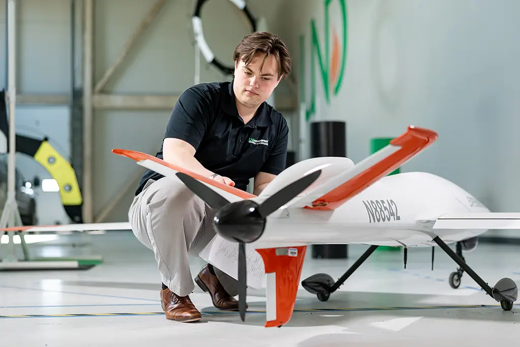 Greyson orne working with a drone on UND's campus.