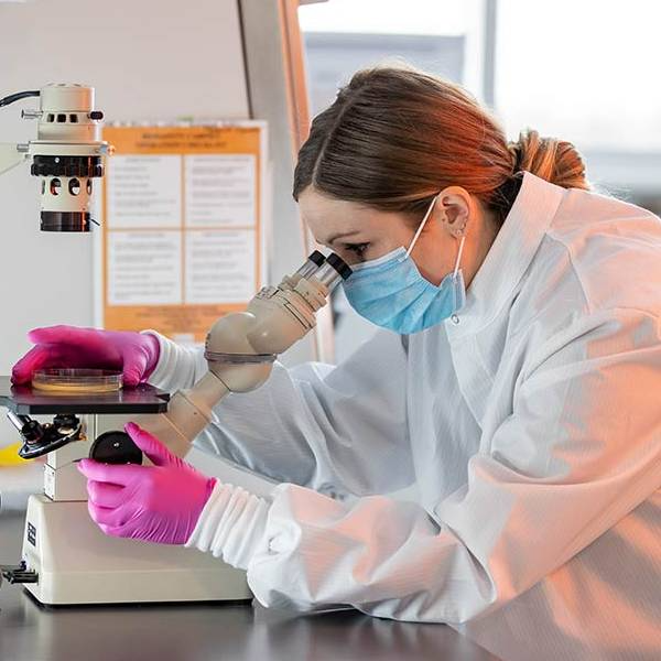 Online MLS student in lab looking through microscope