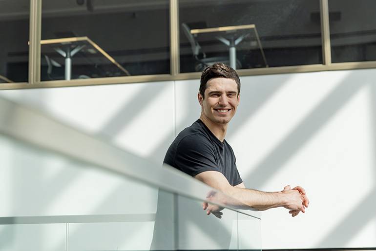 Merrick leaning on railing and smiling