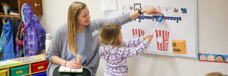 speech pathologist degree student with child