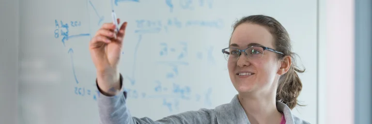 Engineering degree students writing on whiteboard