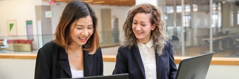 two policy students working on laptops