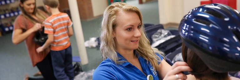 public health students helping child with bike helmet