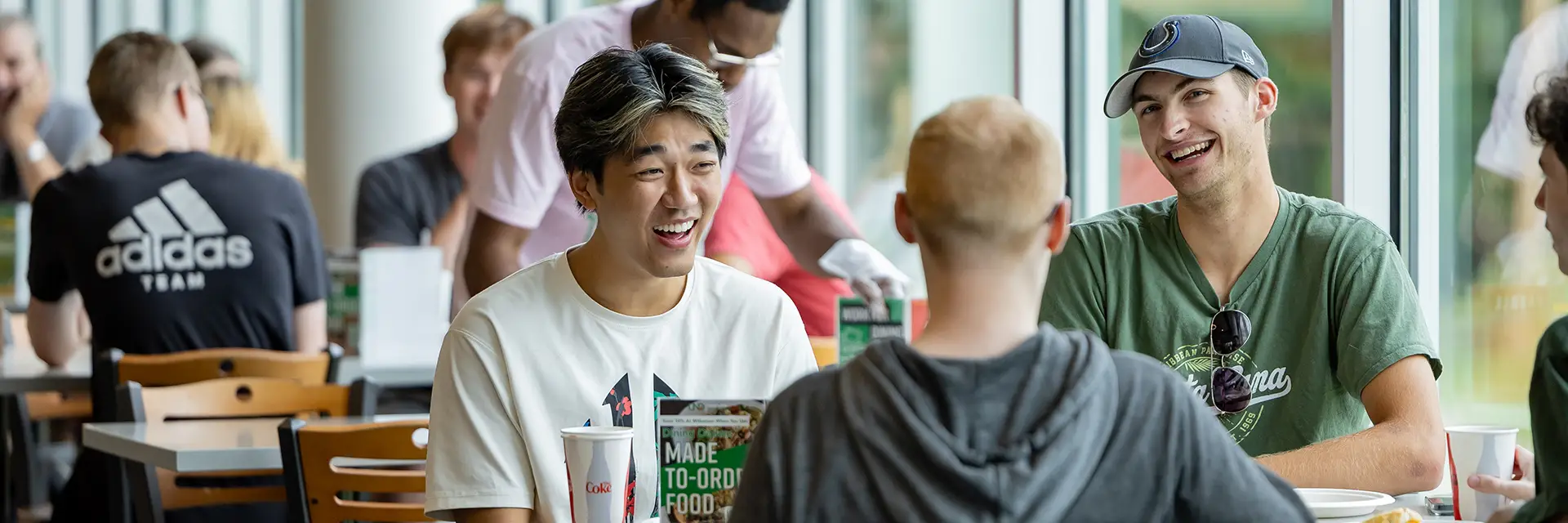 A happy group of young male students have lunch together in the dining center.
