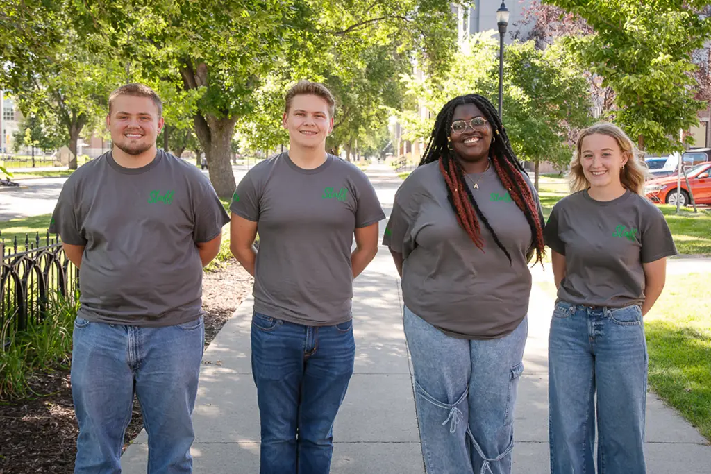 Group of young people pose for a photo with the side walk continuing behind them