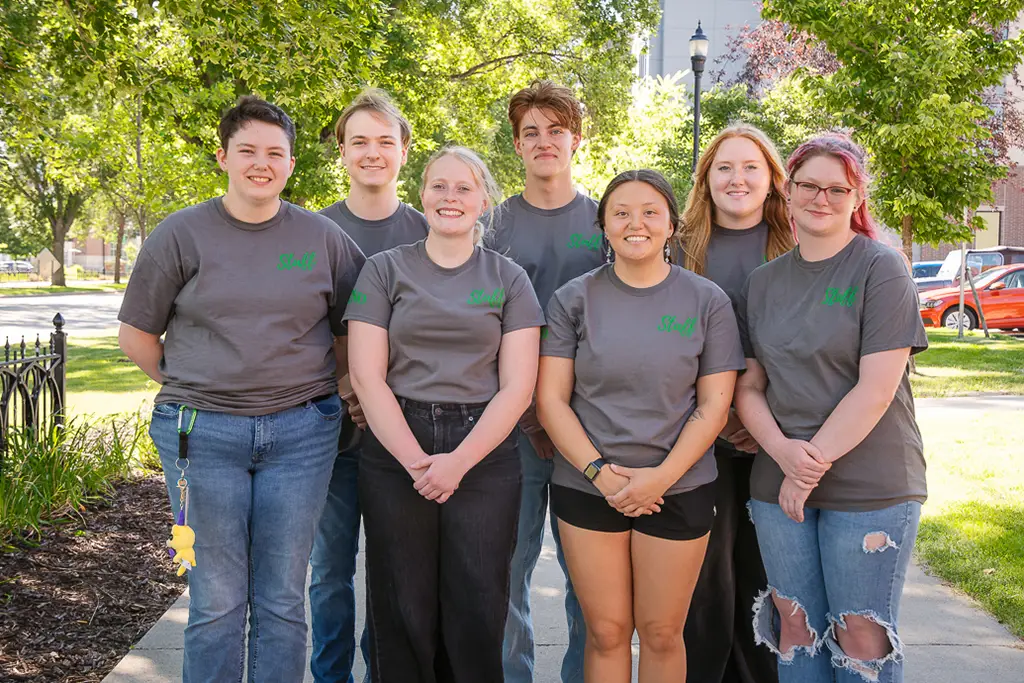 Group of young people pose for a photo with the side walk continuing behind them