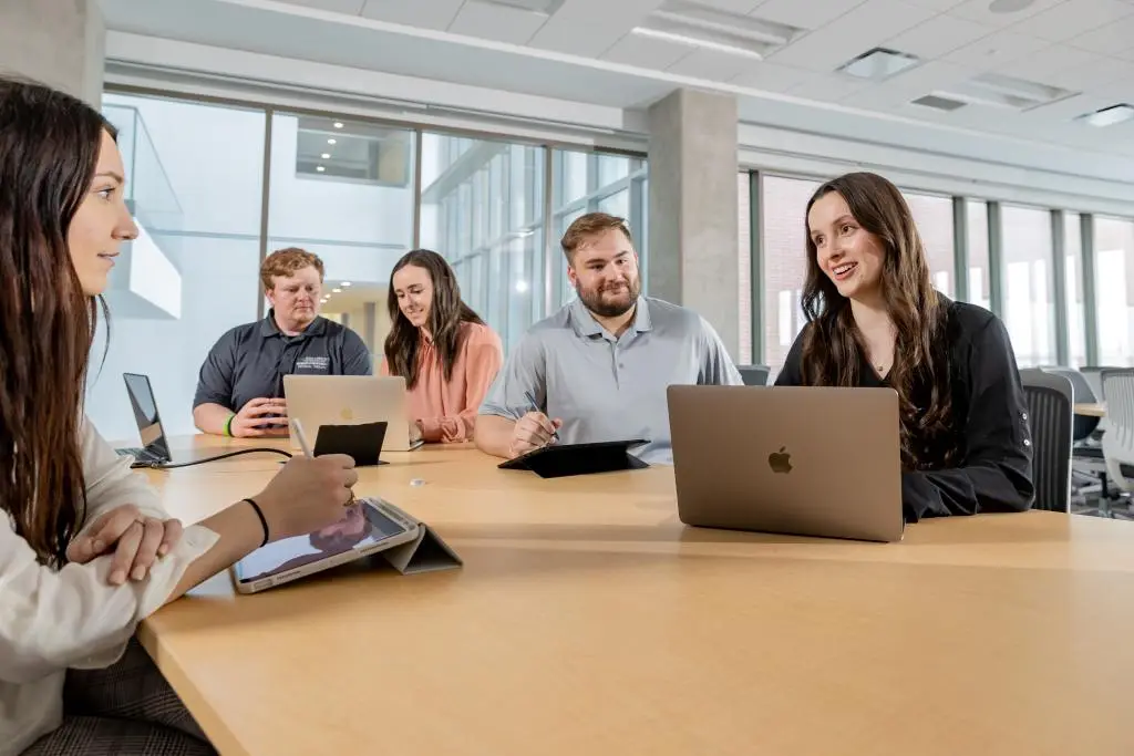 Five people meeting with laptops and a tablet.