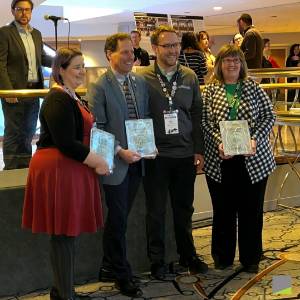 A group of four people hold paper cerificates